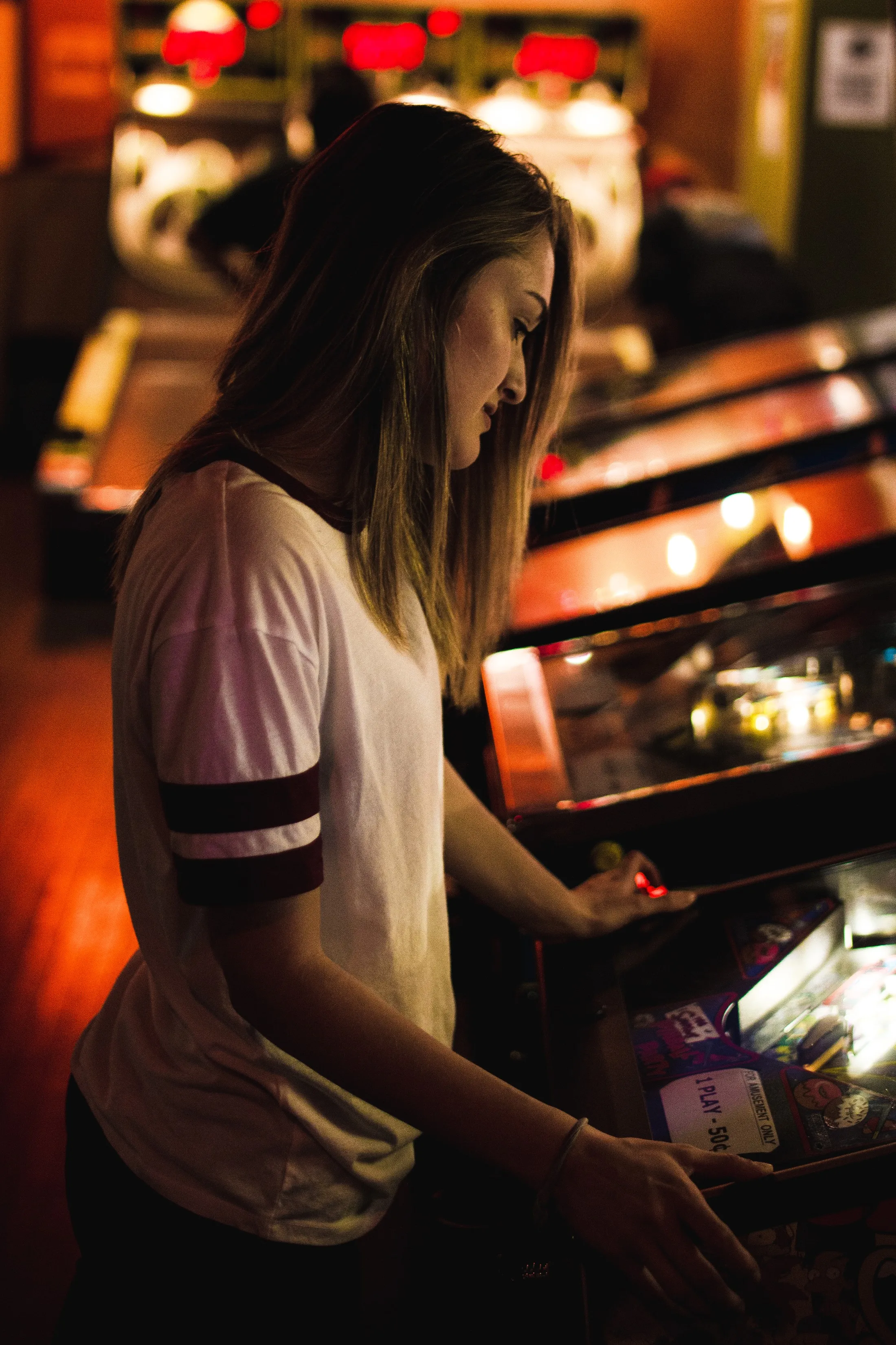 Juli jugando en un arcade con luces cálidas (foto de muestra)